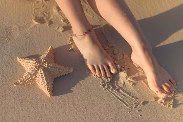 Photo women's feet and starfish on sand