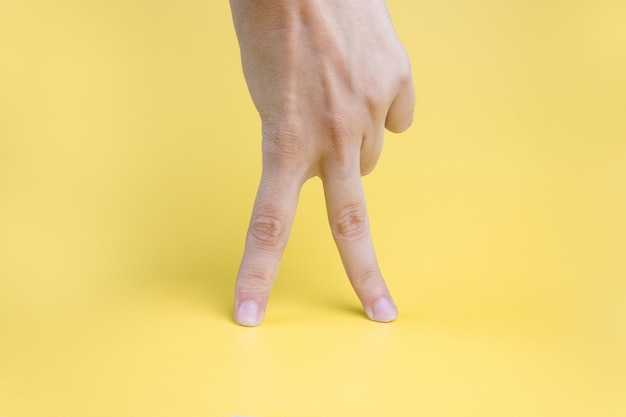 노란색 배경 위를 걷는 여성의 손가락.