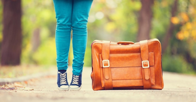 Women's foots near suitcase at autumn outdoor.