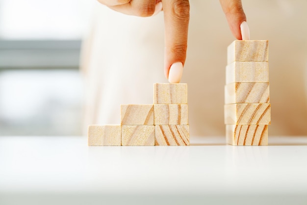 Women's hand folds wooden cubes forming up stairs