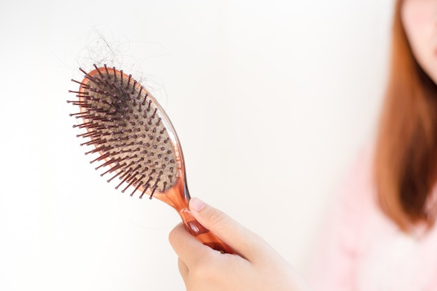 Photo women's hand hair brush with hair loss,   dandruff and health problems.