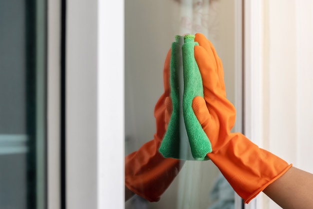 Women's hand wears orange rubber gloves