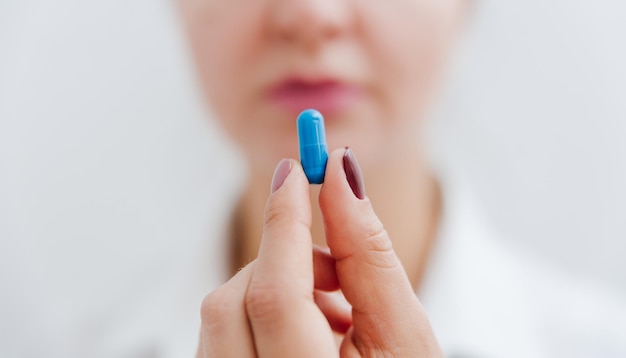 파란색 알약, 비타민, 캡슐이 있는 여성의 손. 의료 보험 치료 개념입니다.