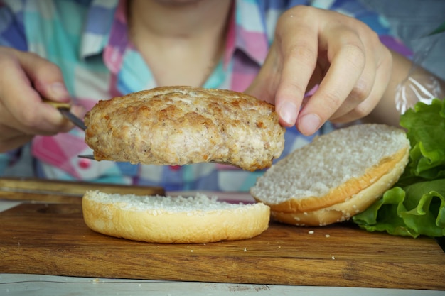 Women's hands are preparing a big hamburger Cheeseburger of the homemade