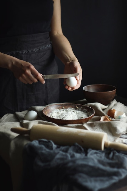女性の手が自家製生麺、素朴、セレクティブフォーカス、雰囲気のあるダークトーンを準備しています