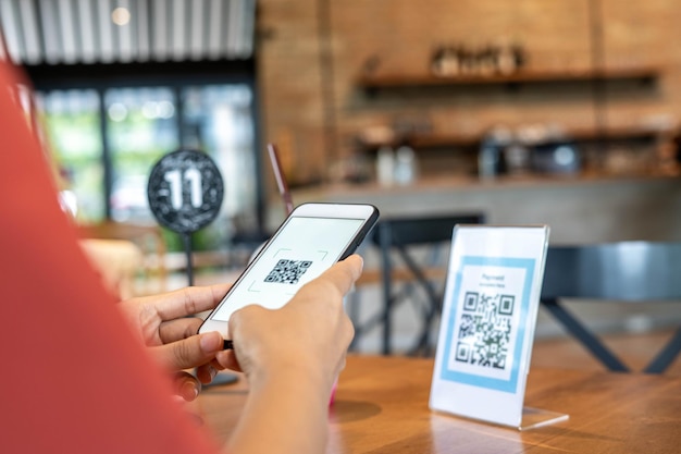 Le mani delle donne usano il telefono per scansionare il codice qr per selezionare il menu del cibo scansione per ottenere sconti o pagare il cibo il concetto di utilizzare un telefono per trasferire denaro o pagare online senza contanti