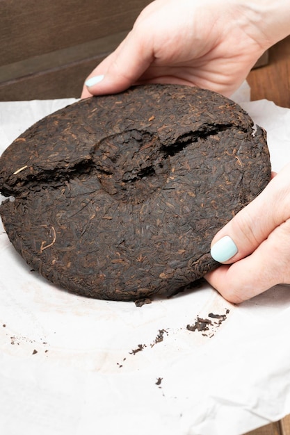 Women's hands break a disc of pressed Chinese Puerh tea Selective focus on breaking a circle of tea