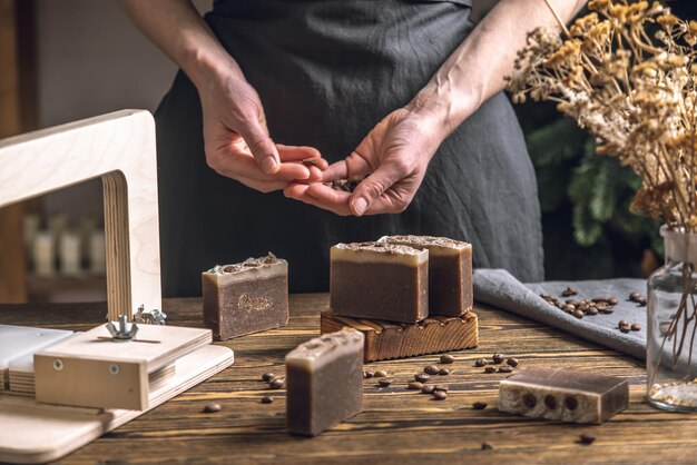 Le mani delle donne tagliano il caffè, il sapone naturale fatto in casa con un taglialegna professionista.