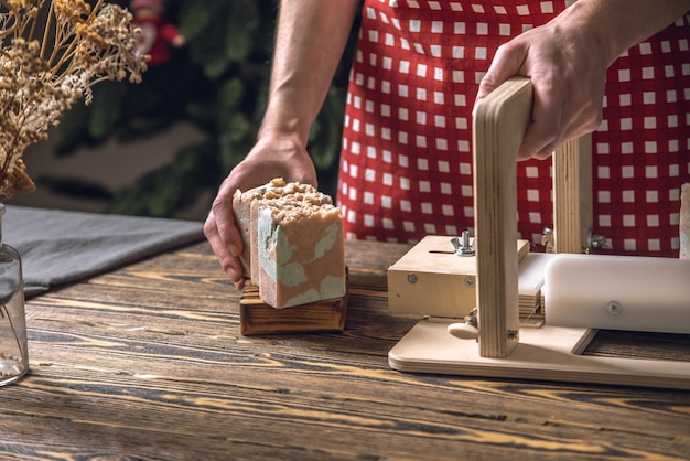 Women's hands cut homemade natural soap on a professional wood cutter A means of ecofriendly hygiene