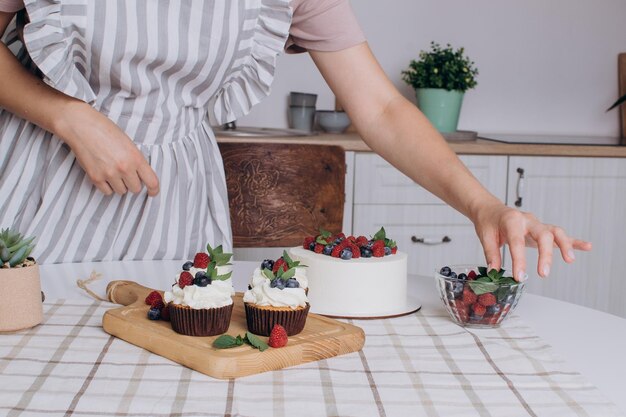 Women's hands decorate cupcakes with cream. Pastry chef profession concept.