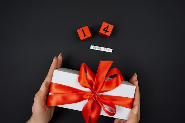 In women's hands, a gift with a red ribbon