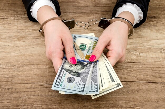 Women's hands in handcuffs with dollars in their hands