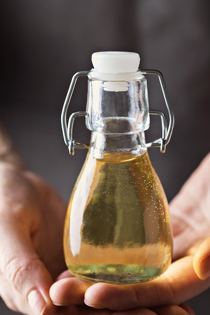 Foto le mani delle donne tengono una bottiglia di vetro con olio vegetale. avvicinamento.