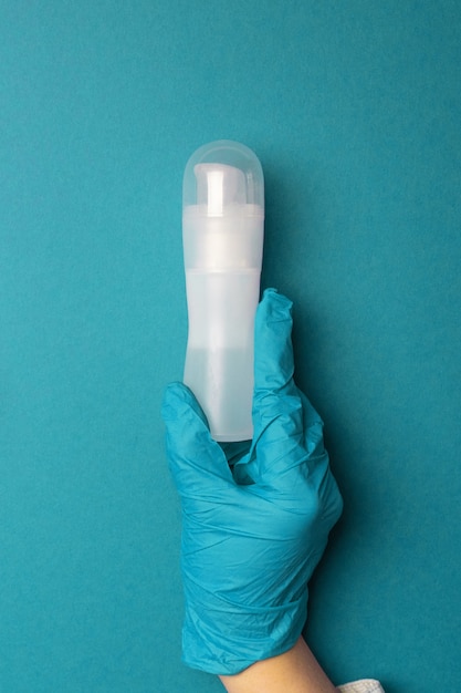 Women's hands hold intimate lubricant on blue background. Vertical photo. View from above.