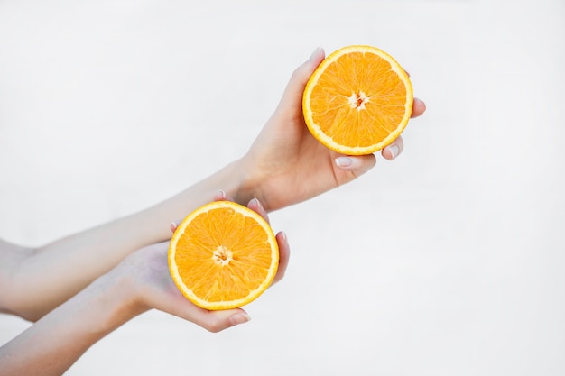 Women's hands hold a juicy half orange isolated on white