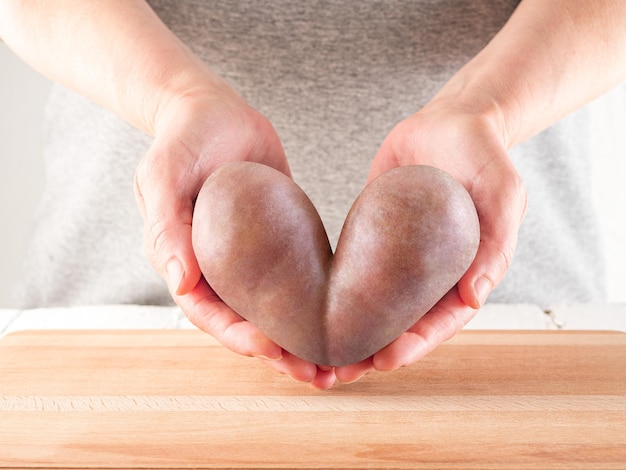 Photo women's hands hold potatoes shaped like a heart