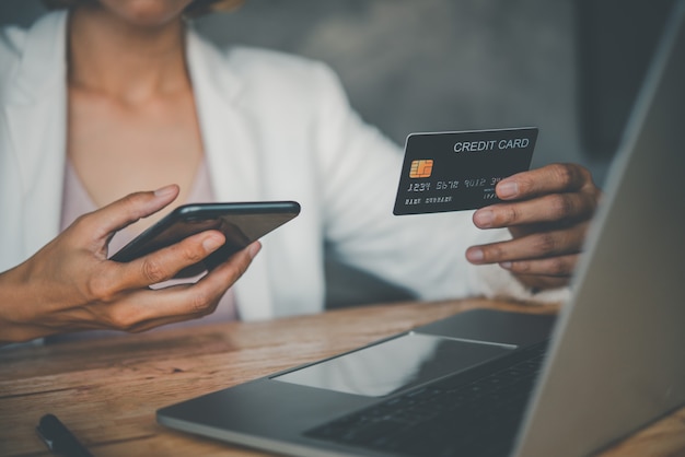 Foto le mani delle donne che tengono una carta di credito e lavorano sul laptop pagamento online per lo shopping online