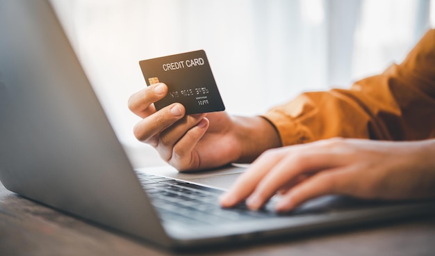 Le mani delle donne che tengono una carta di credito e lavorano sul laptop pagamento online per lo shopping online