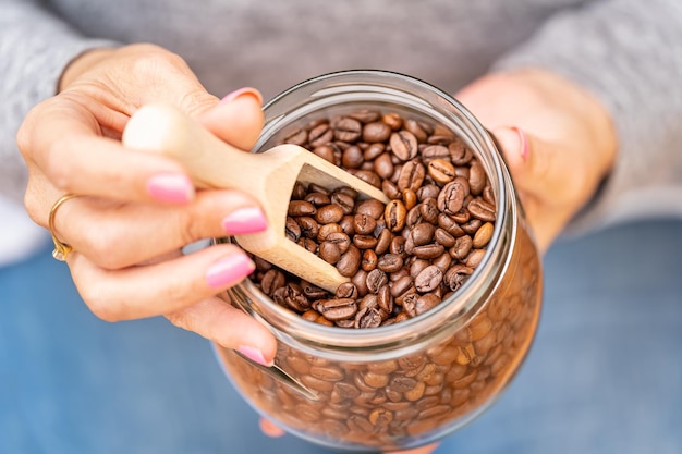 Women's hands holding a glass jar full of coffee beans