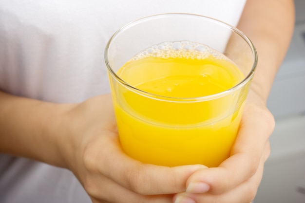 Женские руки, держа стакан апельсинового сока