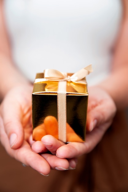 Women's hands holding gold gift box