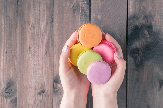 Mani delle donne che tengono macarons