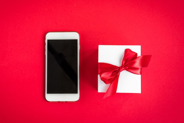 赤のクリスマスの装飾やギフトで携帯電話を保持している女性の手。