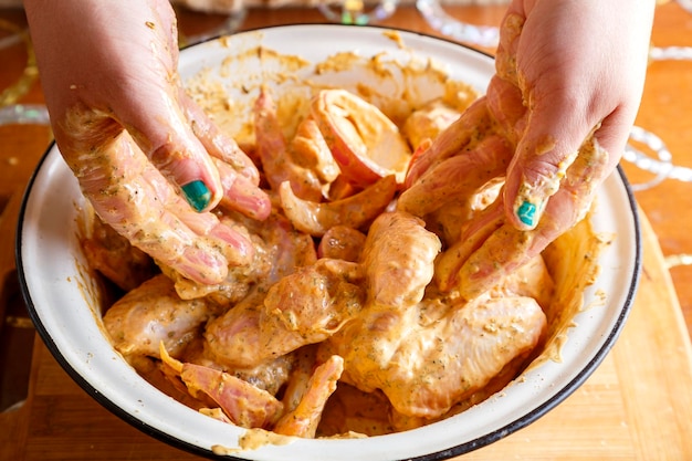 Le mani delle donne marinano le ali di pollo in salsa di soia con succo di limone