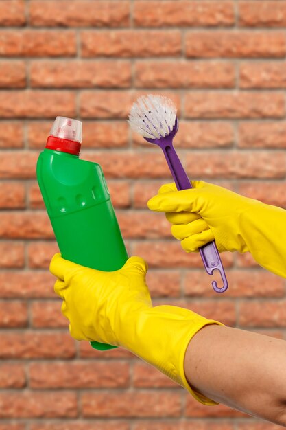 Women's hands in protective gloves with bottle of washing liquid