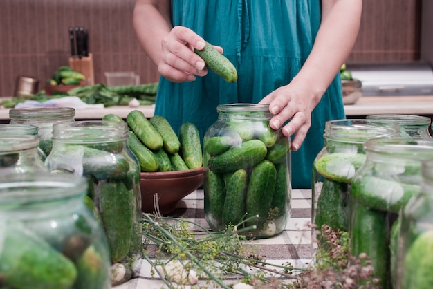 Women's hands put cucumbers in a can for canning