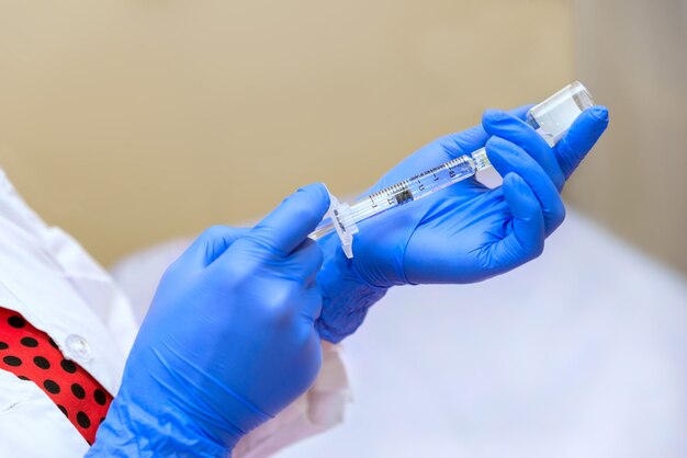 Women's hands in rubber gloves hold syringe with medicine