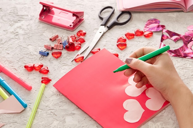 Women's hands sign a handmade valentine's day card