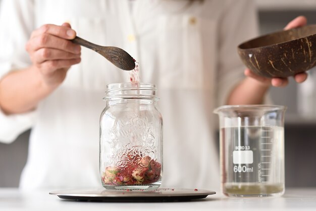 Women's hands throwing dried flowers into a pot making organic cosmetics