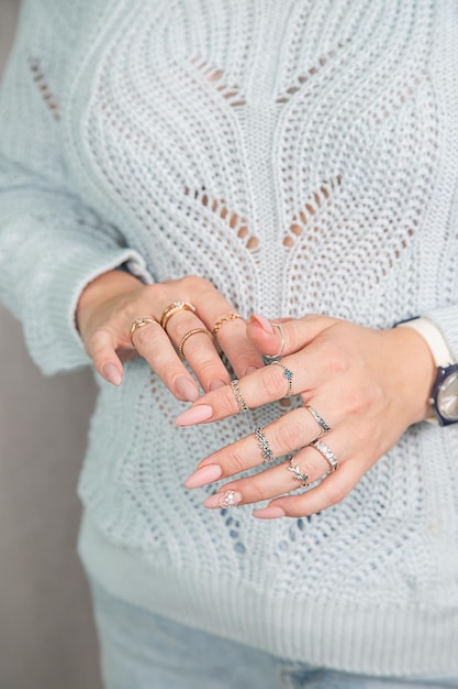 Women's hands with a beautiful manicure and rings are folded on the chest.