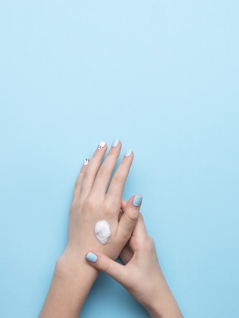 Женские руки с макияжем и каплей крема для рук