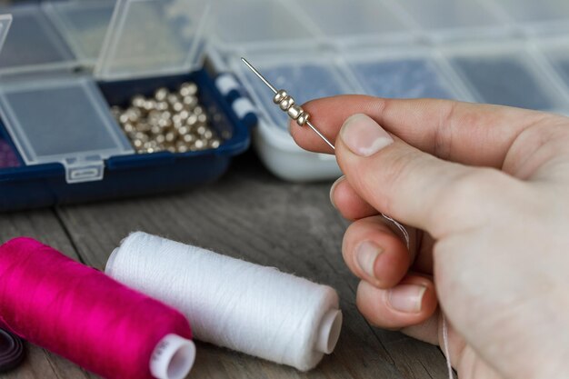 Women's hands with a needle and beads make jewelry