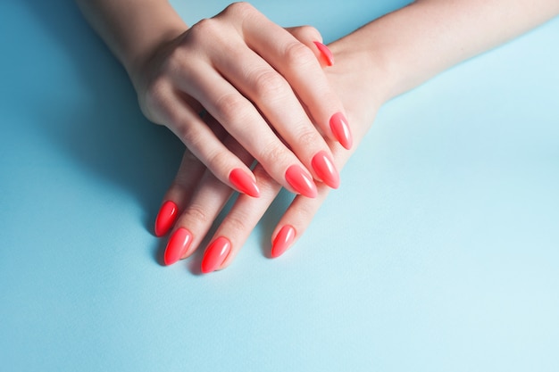 Women's hands with perfect red manicure. Nail Polish red coral color.