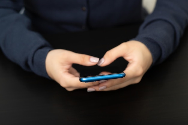 Women's hands with the phone at the Desk in the office