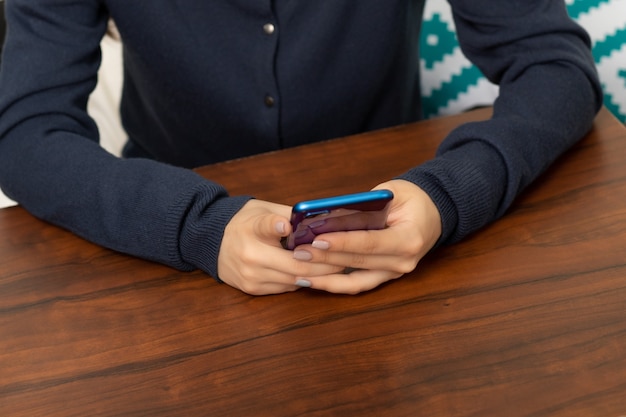 カフェのテーブルでスマートフォンを持った女性の手