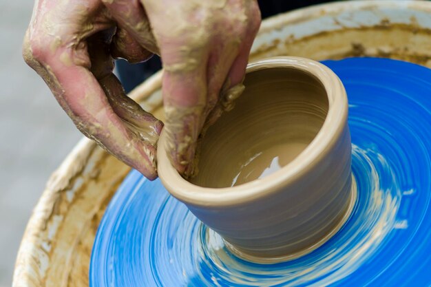 Women's hands work with light clay on a rotating potter's wheel Street master class on modeling of clay on a potter's wheel In the pottery workshop