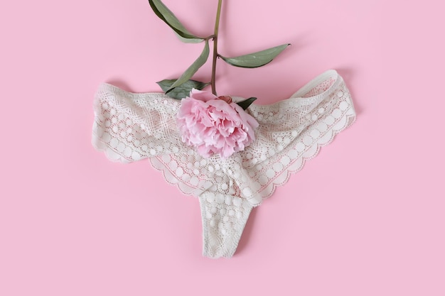 Women's health concept Lace panties with a peony flower on a pink background Flat lay