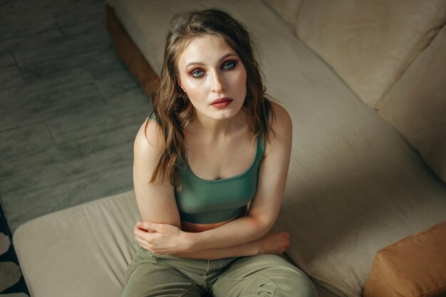 Women's health portrait of a young woman sitting on a sofa and her hands on her stomach