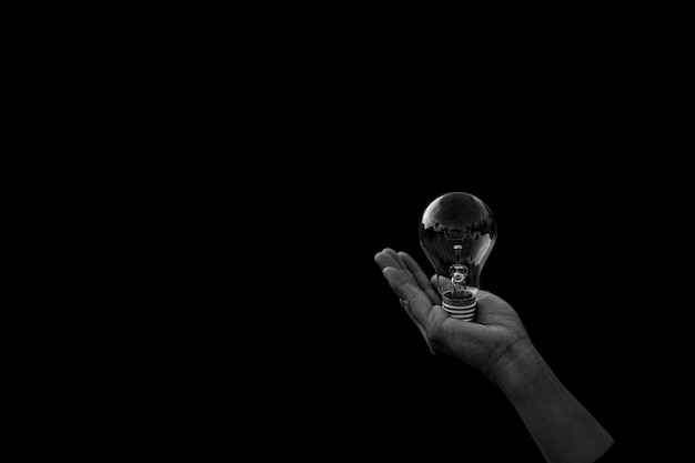 女性は暗闇の中で電球を保持しています。 -新しいアイデアとイノベーションのコンセプト。