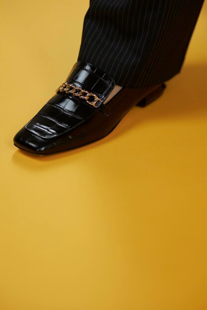 Women's lacquered black loafers closeup on a yellow background Women's loafers Style and fashion