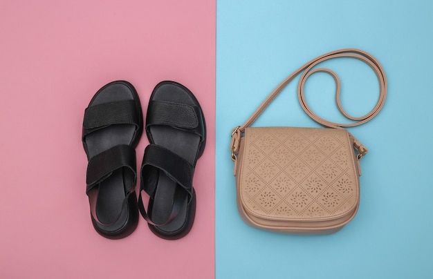 Women's leather sandals and bag on pink blue background. Women's accessories. Top view. Flat lay