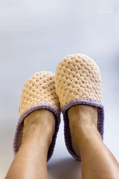 Women's legs in knitted peachcolored slippers Needlework knitting home comfort