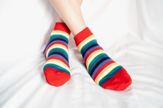 Women's legs in socks colors alternating, side stand on white fabric floor.