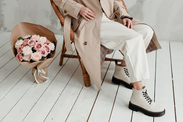 Women's legs on a white background. A bouquet of flowers and a girl's legs. A bouquet of roses at the feet of a woman.