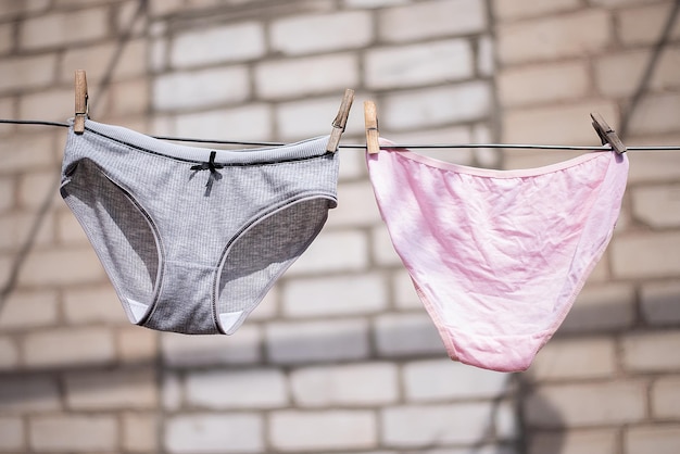 Photo women's panties underwear after washing dry on a rope in sunny weather on clothespins background bricksxa