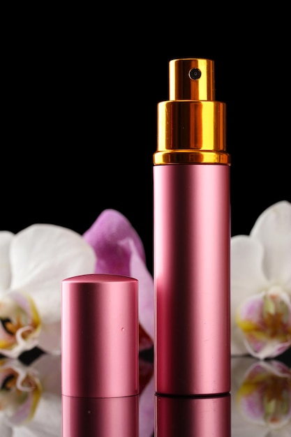 Photo women's perfume in beautiful bottle and orchid flowers on black background